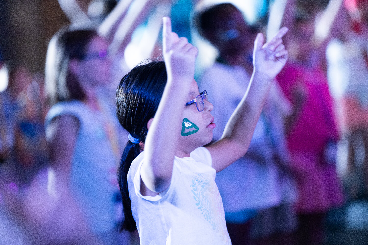 little girl raising hands in worship