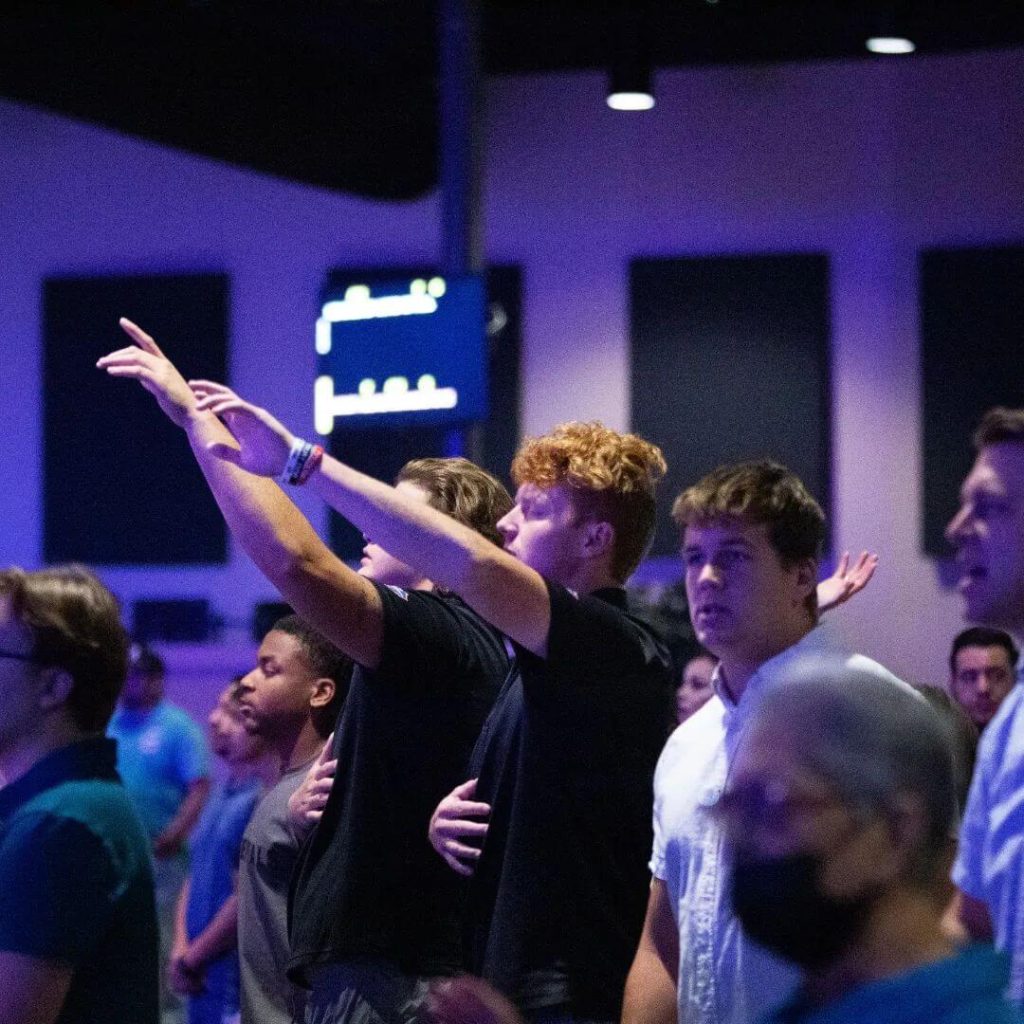Men with hands raised in worship at Real Life Church in Las Curces, NM.